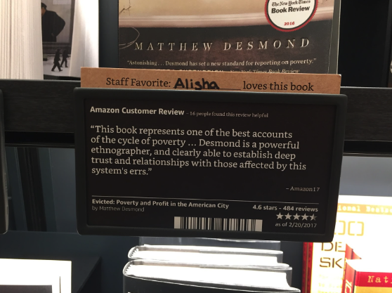 A small physical sign featuring an Amazon customer review next to books. 