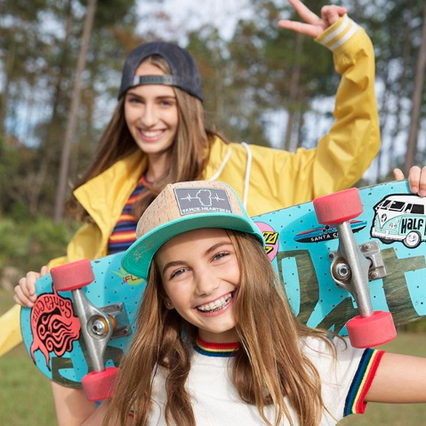 Teen girls in hats with skateboards in a park