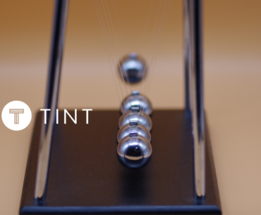 Marble Impact on Newton's Cradle next to TINT logo