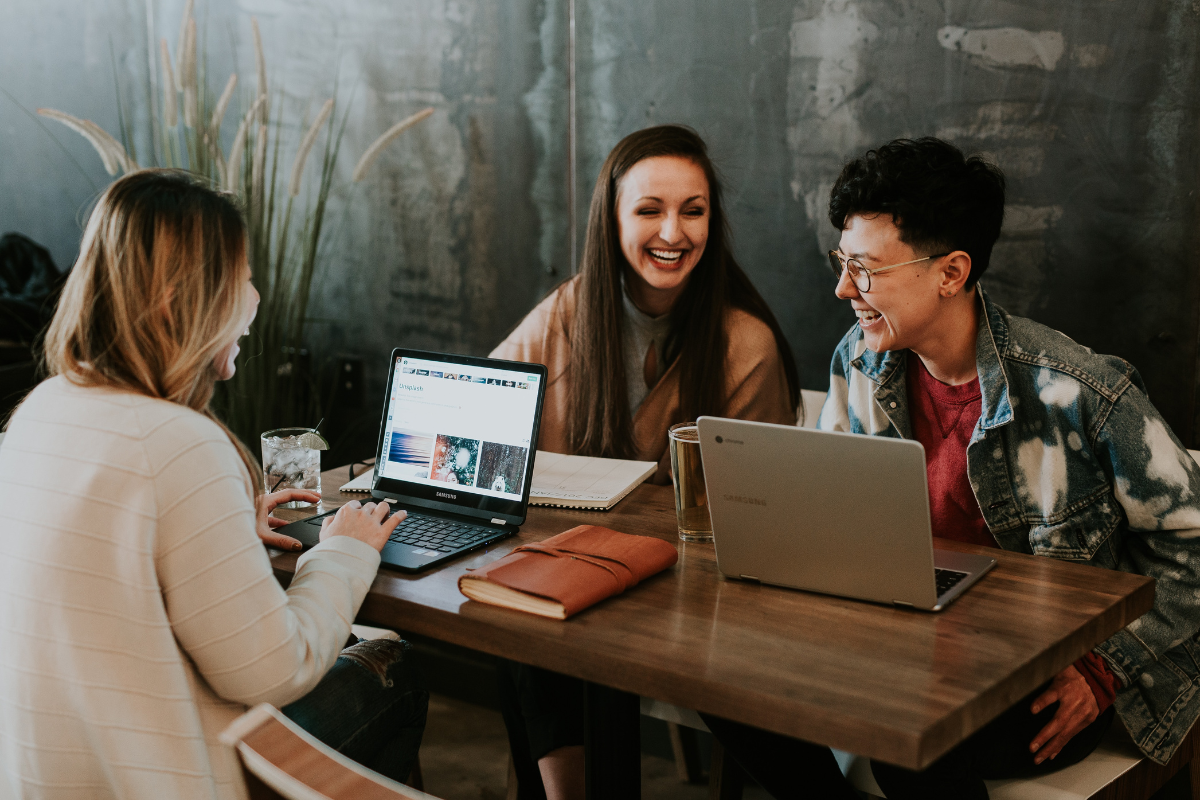 A small group of people sharing a table, sitting around their computers