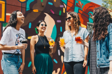 Four friends, each with a beverage in their hand