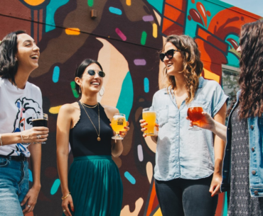 Four friends, each with a beverage in their hand