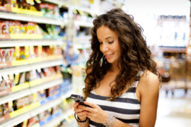 Woman consulting her phone in grocery aisle