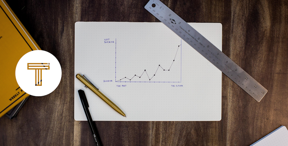 TINT logo next to graph paper featuring a chart on a wooden table