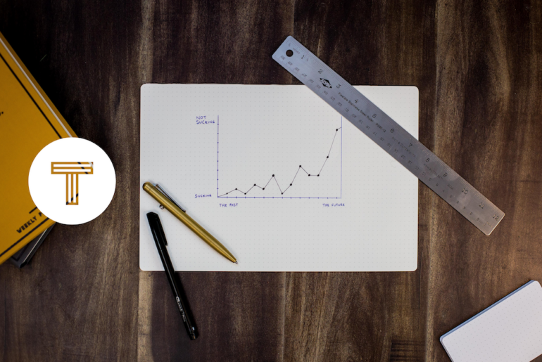 TINT logo next to graph paper featuring a chart on a wooden table