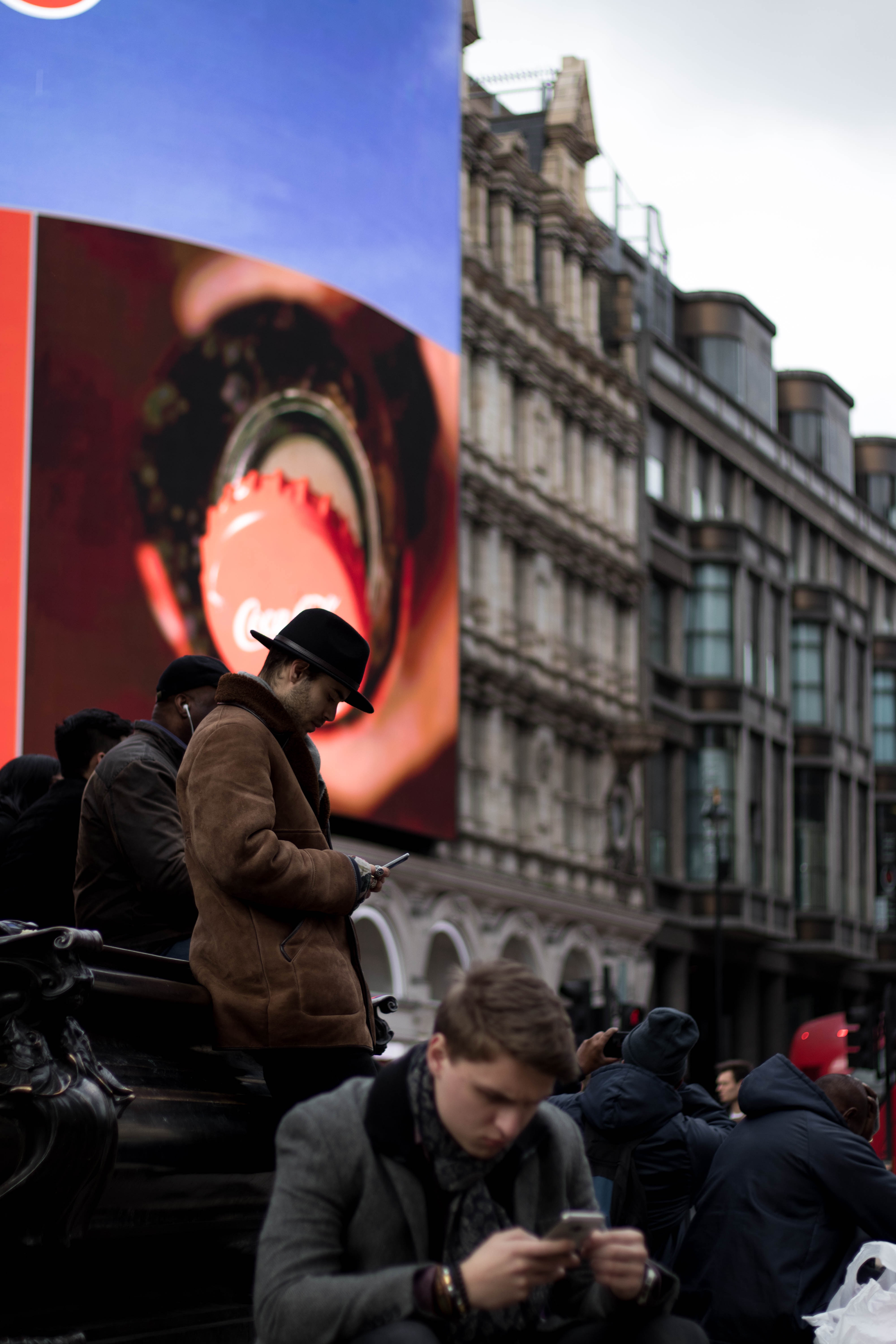 People on mobile phone in front of advertisement