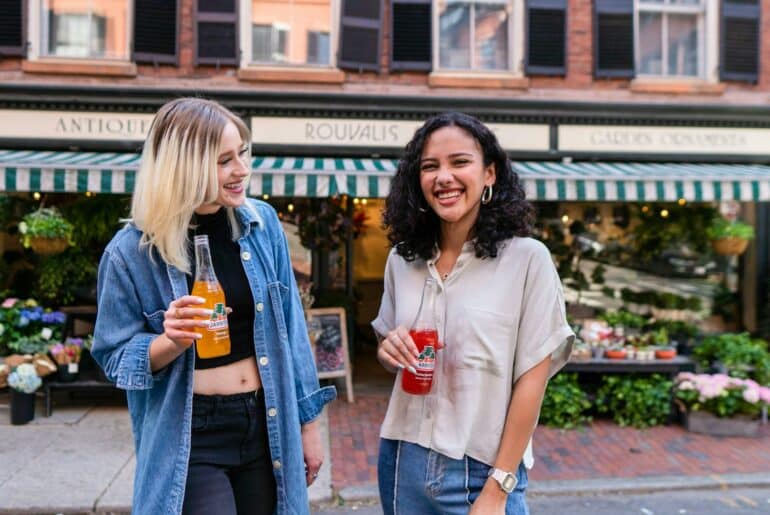 Two brand ambassadors holding product and smiling in front of a shop