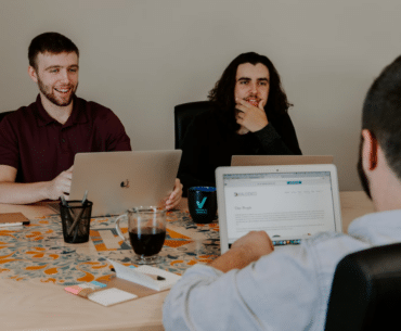 three men on their laptops, collaborating