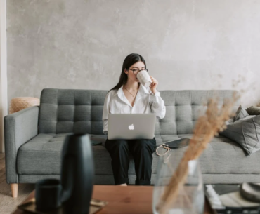 A woman drinking coffee as she's on her laptop