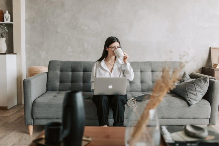 A woman drinking coffee as she's on her laptop