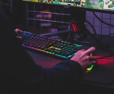 Man playing PC game on colorful keyboard and mouse