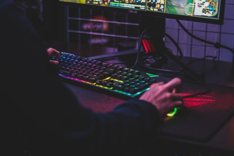 Man playing PC game on colorful keyboard and mouse