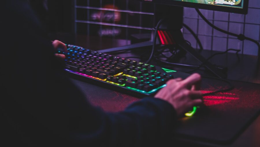 Man playing PC game on colorful keyboard and mouse