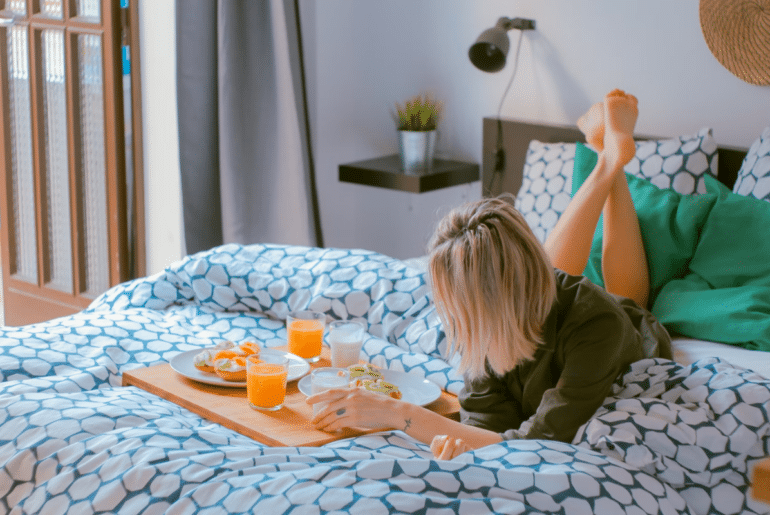 A woman laying in bed with breakfast in bed