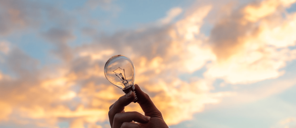 A person holding a lightbulb towards the sky