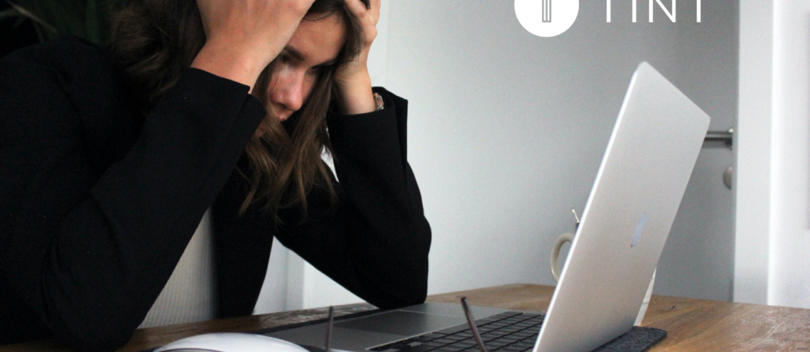 woman holding her head while working at laptop