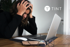 woman holding her head while working at laptop