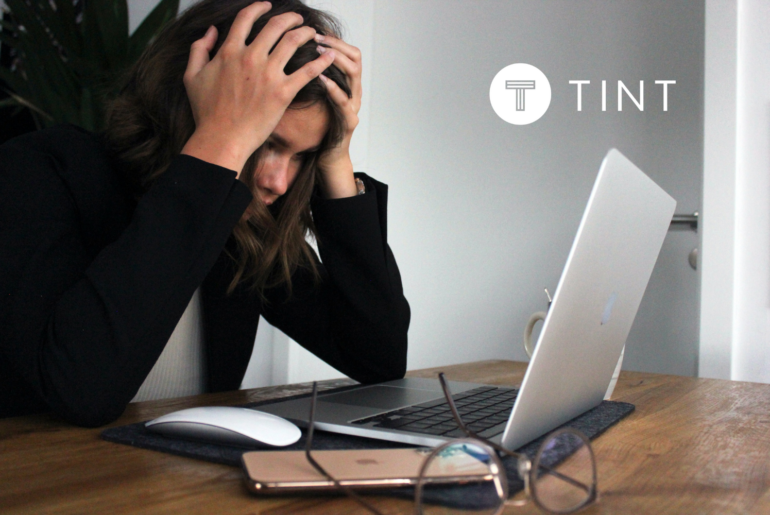 woman holding her head while working at laptop