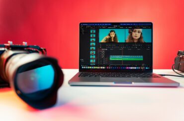 A camera beside a laptop displaying a video of a woman being edited