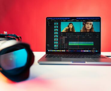 A camera beside a laptop displaying a video of a woman being edited