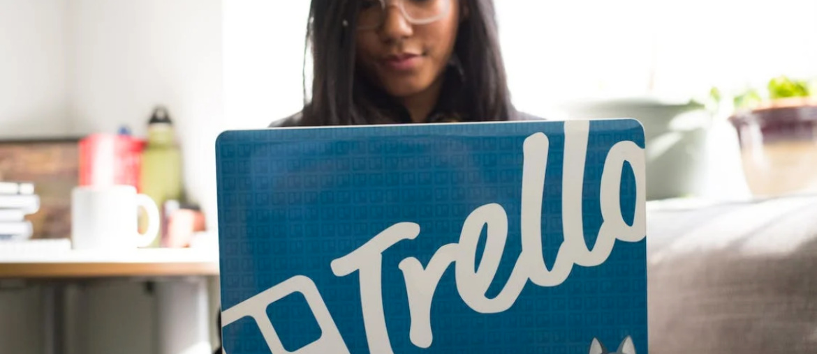 A woman on her laptop with a sticker that says Trello