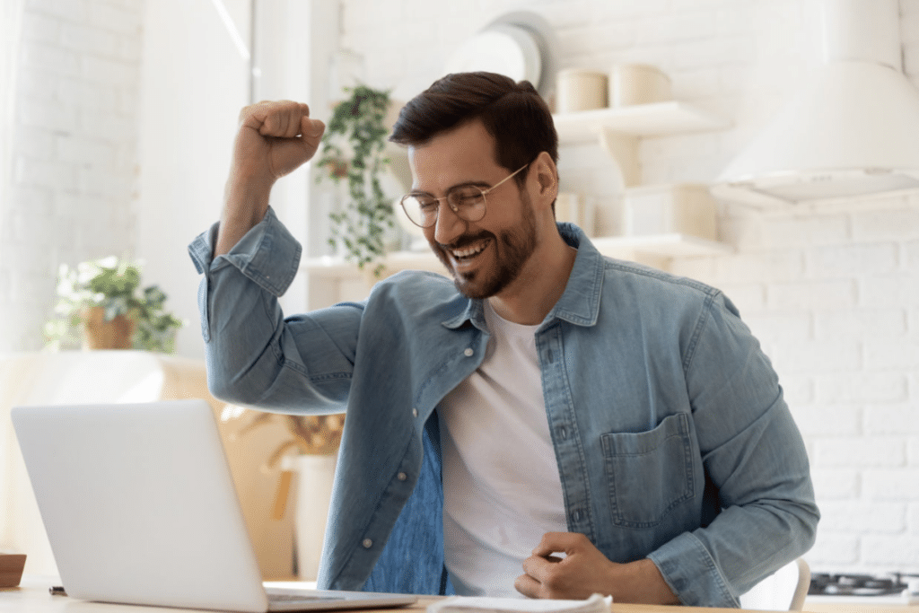 A man first bumping in the air as he looks at his laptop screen