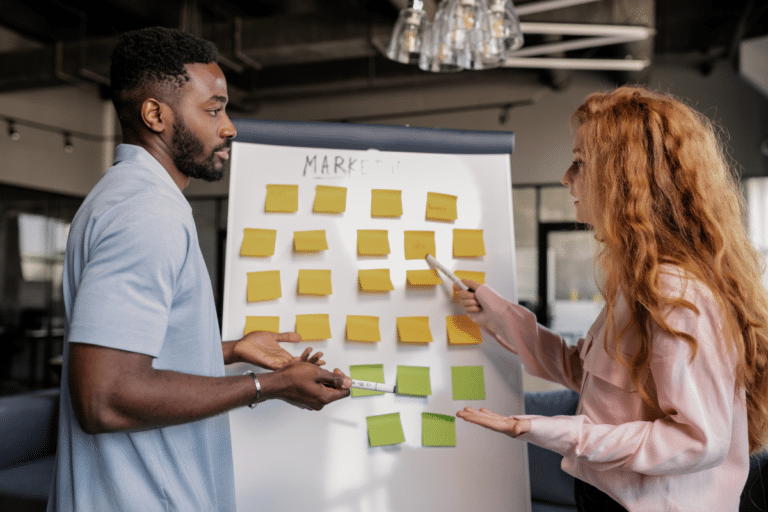 A man and woman collaborating with post-its on a board