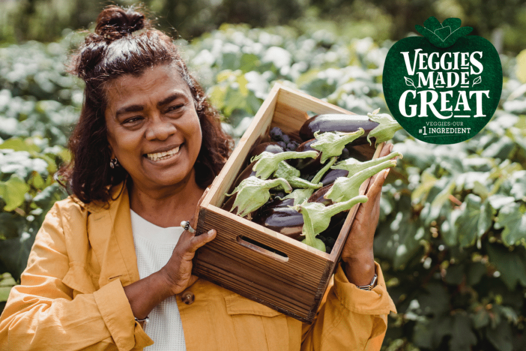 A woman carrying a box of eggplants