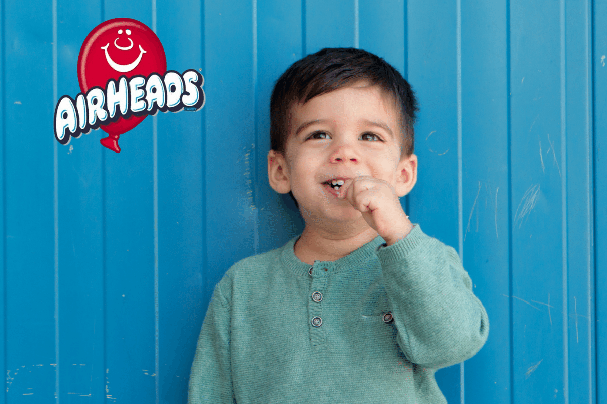 Boy in front of blue wall with Airheads logo