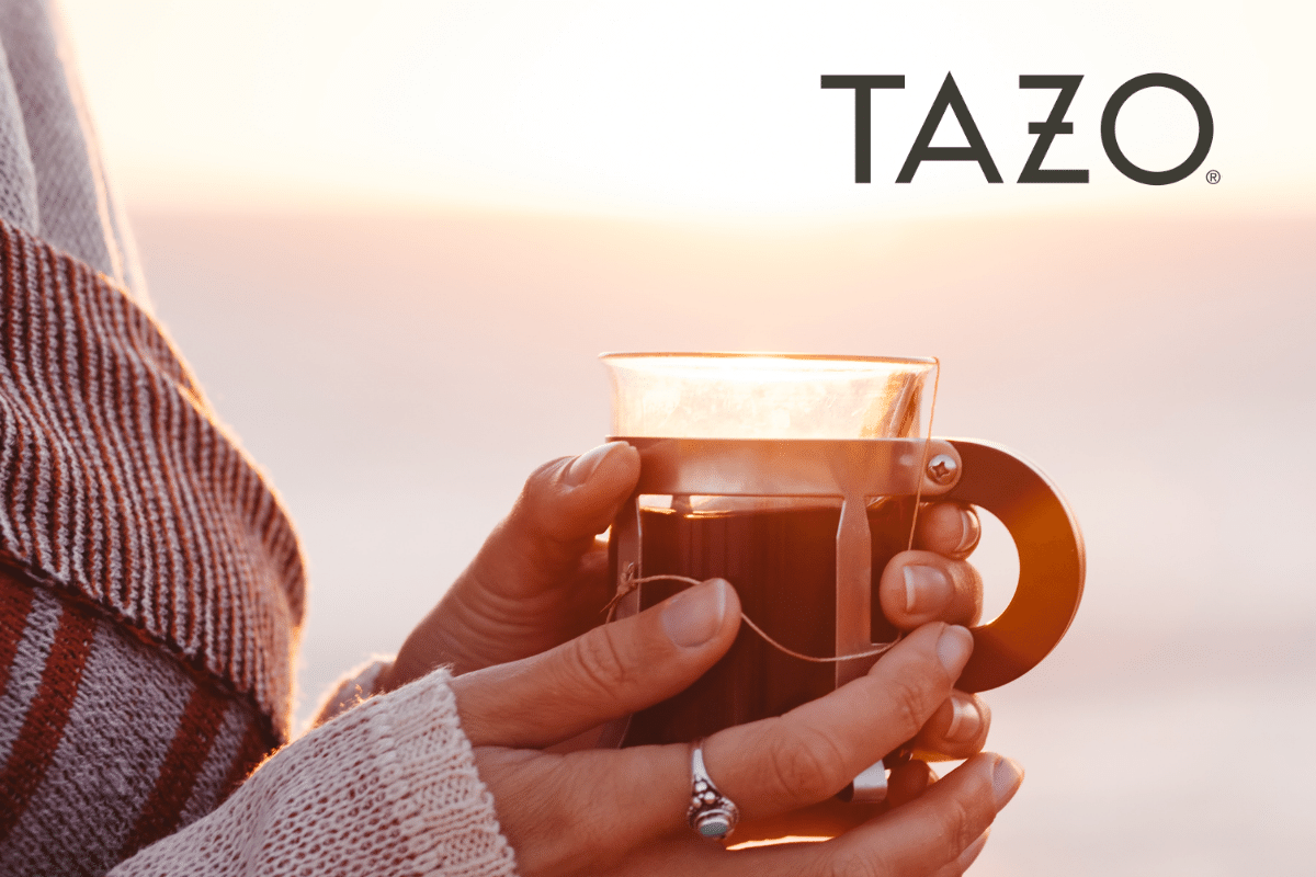 Hands holding a tea cup with TAZO logo