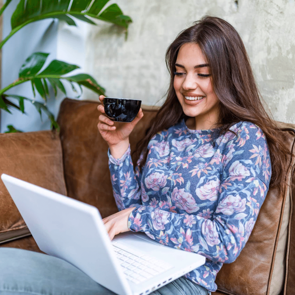 Image of a woman looking at a laptop with a cup of tea